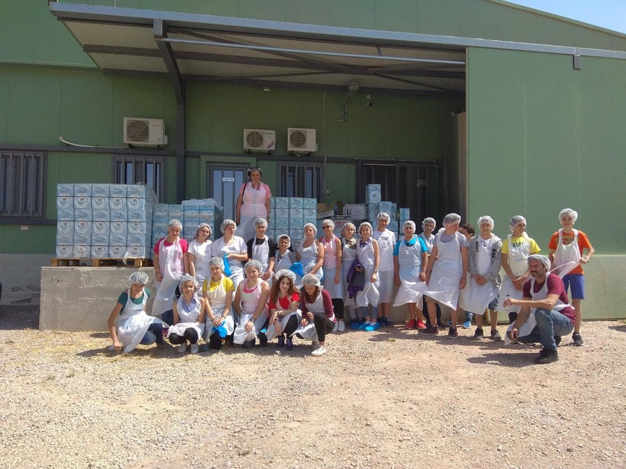 a group of women and men dressed in working forms watching at the camera front of 'Mystakelli Dairy' building plant